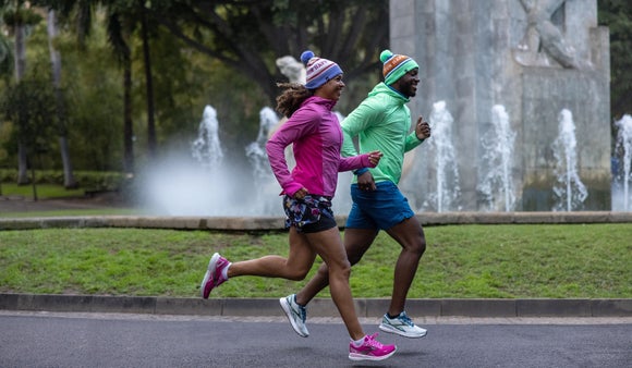 man and women wearing shorts and beanies running near a water fountain