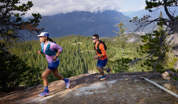 Man and woman running on the trails wearirng hydration vests