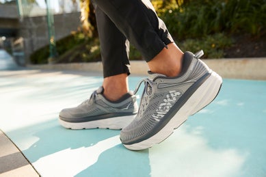 Pair of HOKA Bondi 7 grey running shoes on model's feet