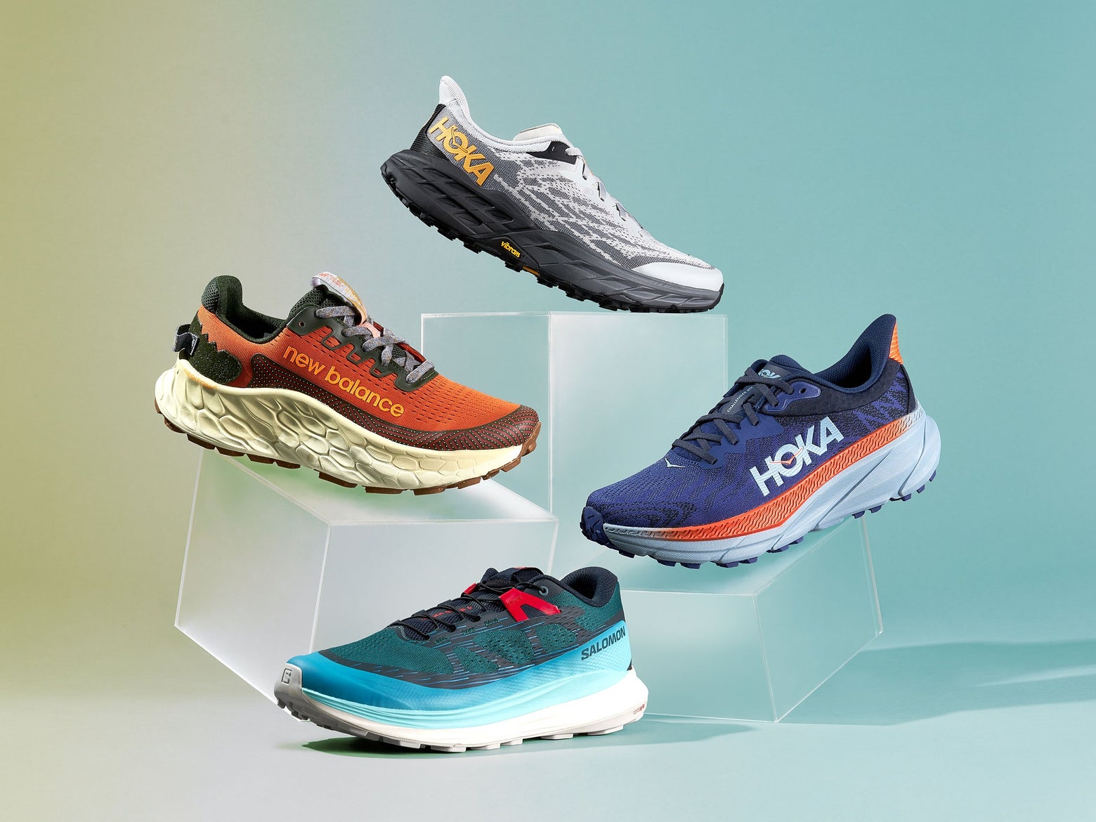 Four trail running shoes stacked on top of boxes