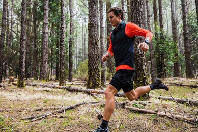 trail runner running through the forest wearing a GPS watch