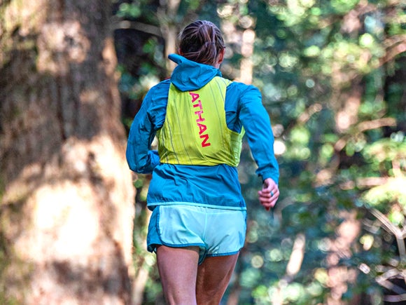 Female runner in nature wearing the Nathan Pinnacle hydration vest