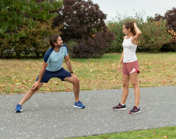 Male runner stretching and female runner standing
