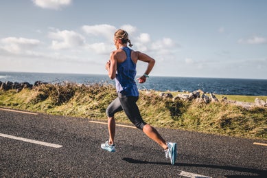 woman running on road by ocean