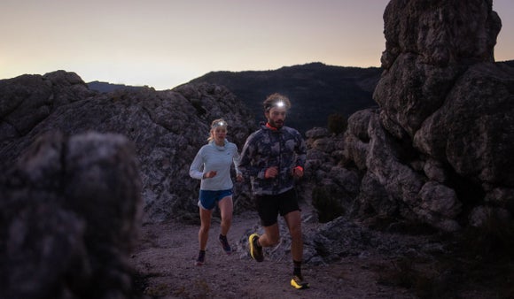 man and women wearing headlamps and trail running