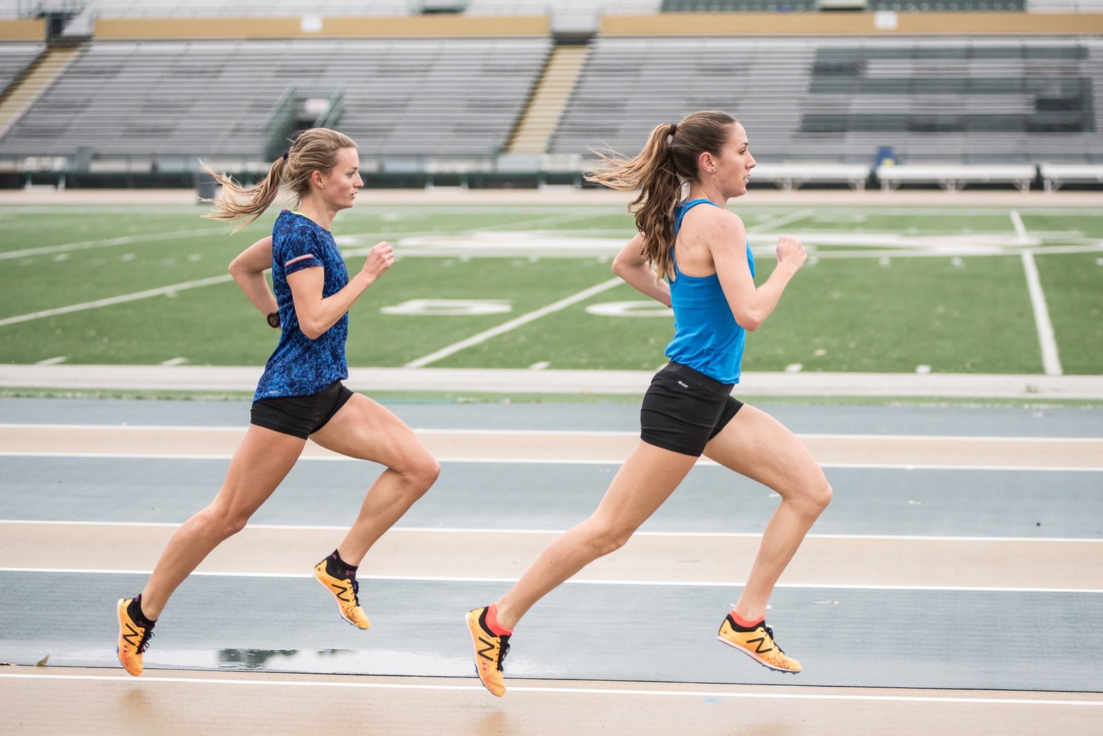 Two female track athletes running on the track