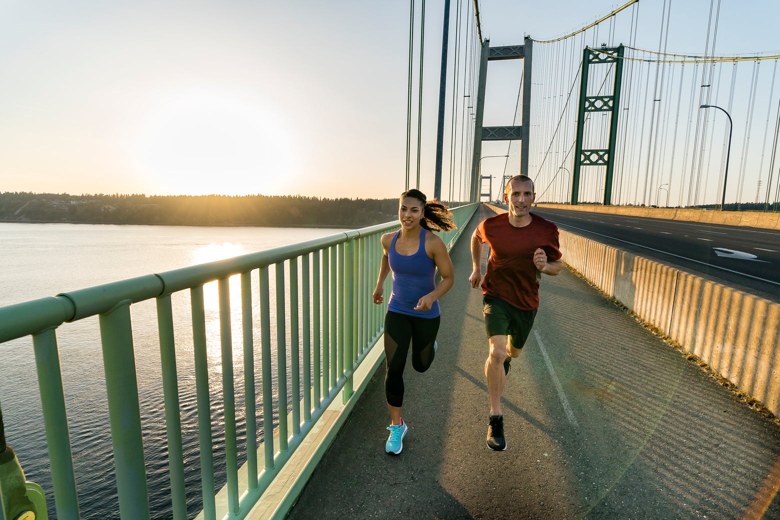 man and woman running across bridge