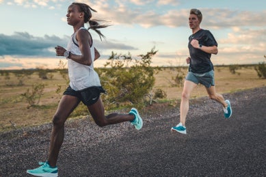 Male and female runner running on a paved road
