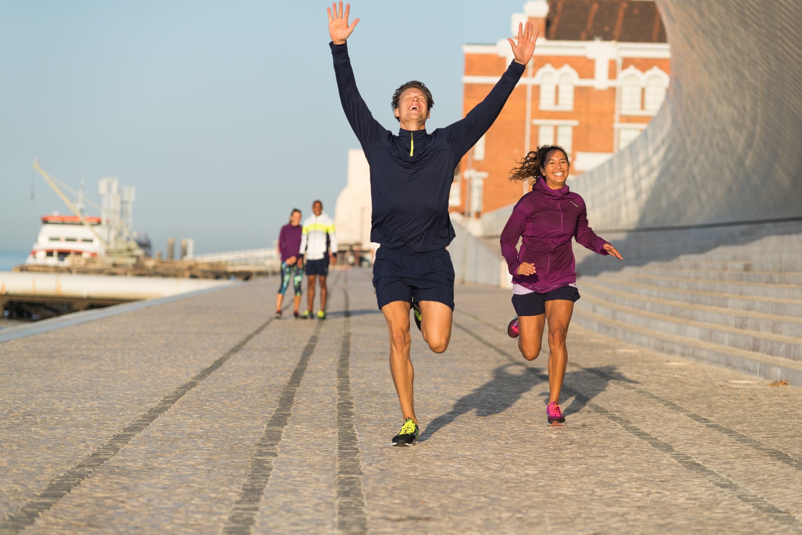 man and women laughing and running in city