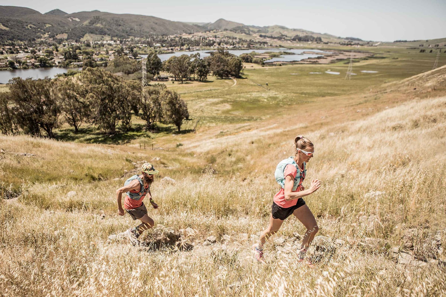 Man and woman trail running with hydration vests