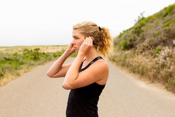 A runner putting on her AfterShokz headphones