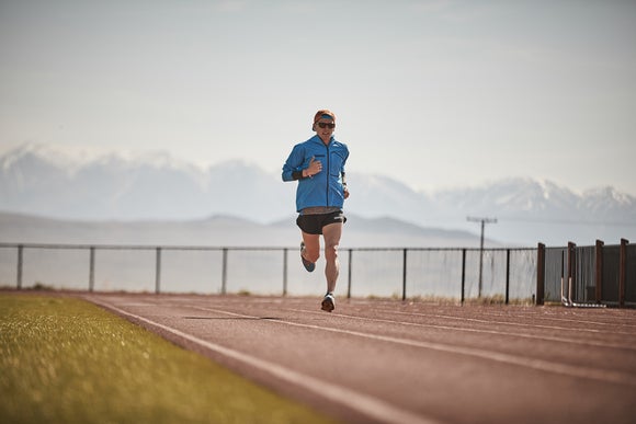 man running on track with mountains behind
