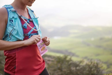 women opening nutrition packet wearing a hydraiton vest