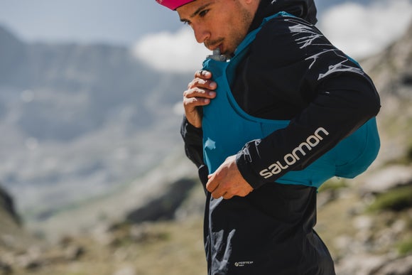 trail runner in the mountains drinking out of his Salomon Sense Pro Set Pack in ocean blue